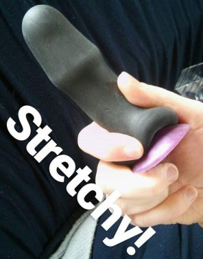 Demonstrating the Buck-Off's give by stretching it down a slim purple dildo